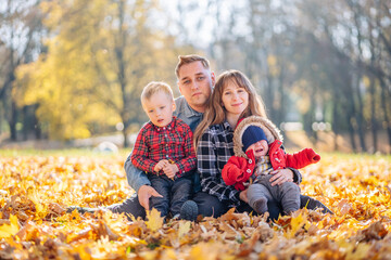 A young family sits in the park on a leafy, sunny autumn day.