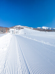 Fototapeta na wymiar Freshly pressed piste in a quiet ski resort at early morning on a clear day (Niseko Moiwa, Hokkaido, Japan)