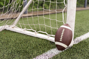 Close up view of an American Football sitting on a grass football field on the yard line. Generic...