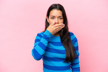Young Colombian woman isolated on pink background covering mouth with hand