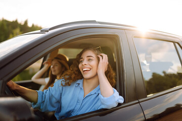 Portrait of two young women on a car trip having fun, smiling, chatting together, enjoying nature. Active lifestyle, travel, tourism, nature.