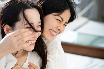Young Asian females having fun at a seaside restaurant terrace, smiling joyfully	
Friendship and...