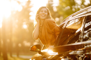 Feeling of freedom on beautiful sunny summer road. Shot of an attractive woman leaning out of car window while driving. Active lifestyle, travel.