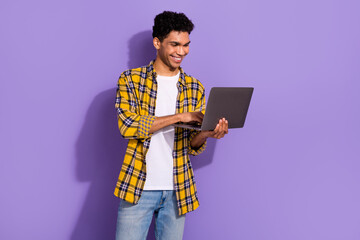 Portrait of good mood smart man with afro hairstyle wear plaid shirt look at laptop on video call isolated on violet color background