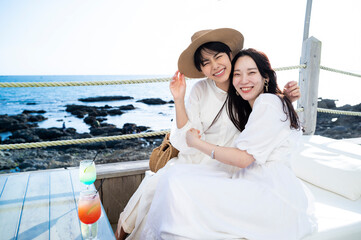 Young Asian females having fun at a seaside restaurant terrace, smiling joyfully	
Friendship and...