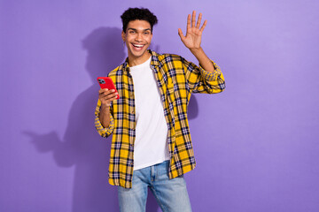 Portrait of cheerful satisfied man with earrings wear plaid shirt hands hold credit card dollars isolated on violet color background