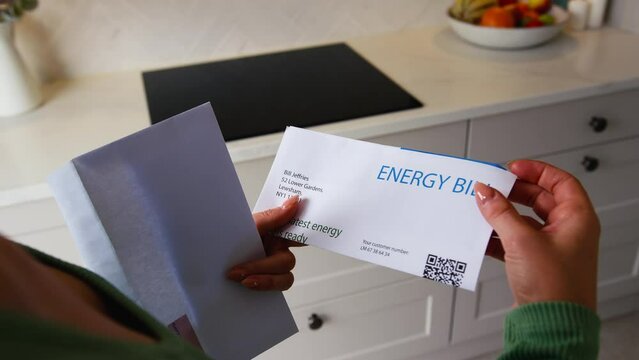 Close up of woman at home opening UK energy bill during cost of living crisis - shot in slow motion