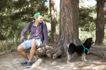 Young man sitting on a tree trunk with his dog in the park