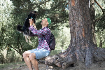 Young man sitting on a tree trunk with his dog in the park