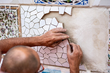 A man renovating Gaudi's mosaic in Parc Guell