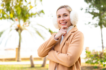 Young blonde woman wearing winter muffs at outdoors smiling