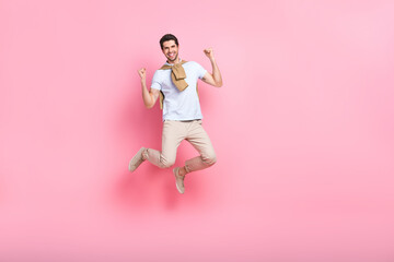 Fototapeta na wymiar Full body cadre of jump positive overjoyed young guy fists up hooray support his favorite football team isolated on pink color background