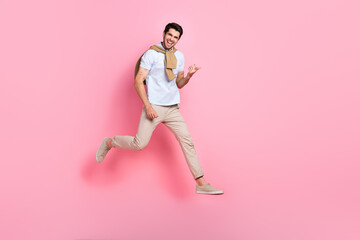 Fototapeta na wymiar Full length portrait of careless sporty man jumping arms play imagine guitar empty space isolated on pink color background