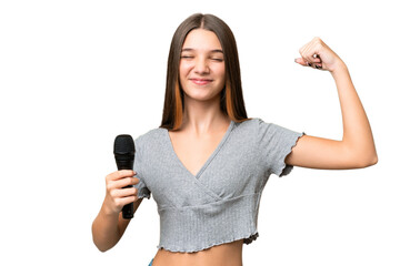 Teenager singer girl picking up a microphone over isolated background doing strong gesture
