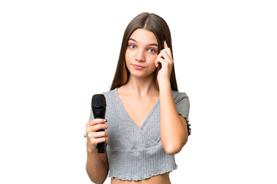 Teenager singer girl picking up a microphone over isolated background thinking an idea