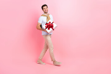 Full body photo of optimistic young boyfriend walking with giftbox package desirable present for...