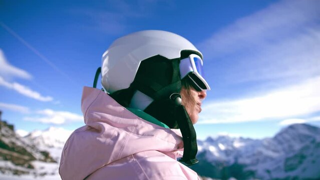 Close-up portrait of woman snowboarder skyer in ski helmet and glasses in mountains, side view. Girl wearing in ski clothes in winter resort. Enjoy healthy sport active rest, snowboarding lifestyle.