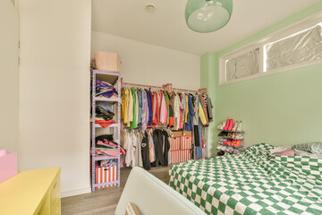 a green and white checkereded bed in a room with two closets on either sides, one is open to the other