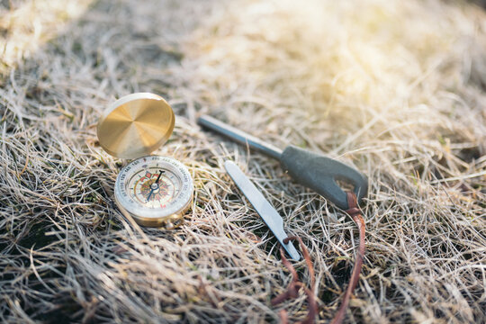Easy to carry vintage compass with mini fire steel and striker placed on dry grass in daylight