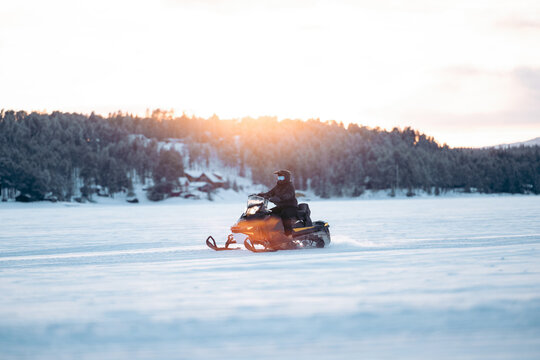 Anonymous person riding snowmobile on snowy ground