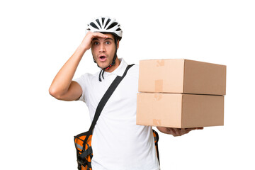 Delivery man wearing a helmet bike over isolated background doing surprise gesture while looking to...