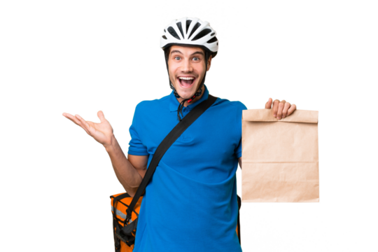 Young caucasian man taking a bag of takeaway food over isolated background with shocked facial expression