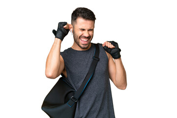 Young sport caucasian man with sport bag over over isolated chroma key background celebrating a...