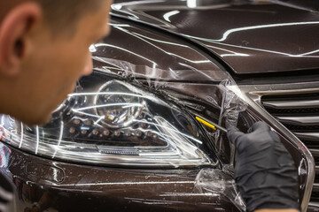 The process of installing a protective polyurethane film for paint on the front headlight of a car. - obrazy, fototapety, plakaty
