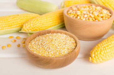 Corn groats and seeds with fresh cobs on wooden table