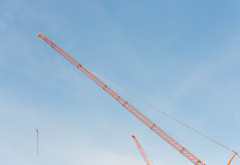 Construction site. Construction cranes and a building under construction against a blue sky background. 