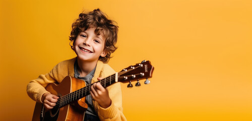 Joyful child playing guitar isolated on flat orange background with copy space. Creative banner for children's music school.
