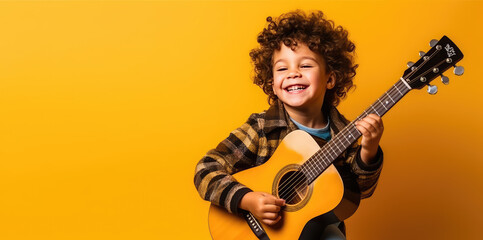 Joyful child playing guitar isolated on flat orange background with copy space. Creative banner for children's music school. - obrazy, fototapety, plakaty