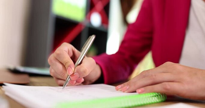 Closeup of businesswoman hands holding pen, makes notes in notebook and performs test task. Woman entrepreneur writes down important data information and creative startup ideas concept