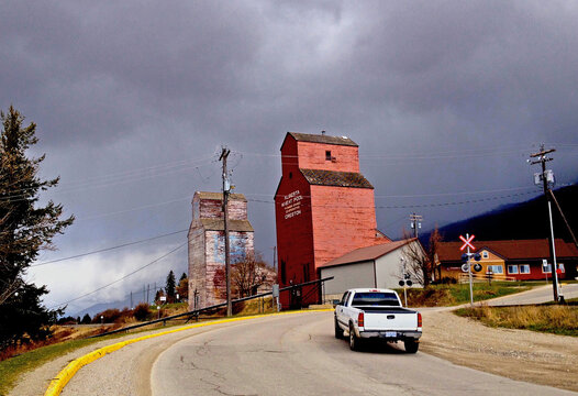 Creston, BC, Canada - April 4 2014 Two grain elevators in Creston. They were built in 1935 and 1936. Dark clouds. A lone pickup on a road called Railway Boulevard.
