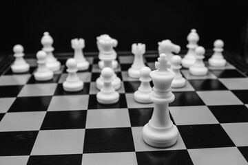 Focus on white chess king with all white chess pieces behind on a chessboard