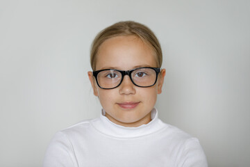Clever child girl in glasses on white studio wall background