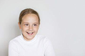 Portrait of happy young girl laughing on white studio wall background