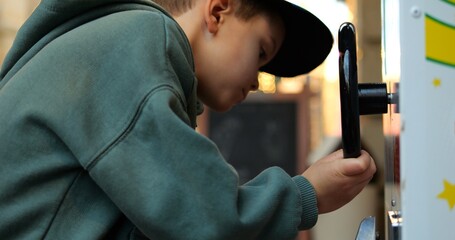 Elementary age child try to catch and collect winnings in street game machine. Boy in zip sweatshirt and cap finished arcade game and reaches for won prize.