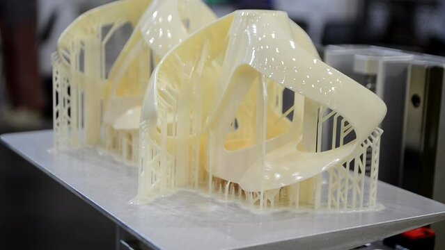 Printed models on 3D printer close-up. Objects printed on photopolymer sla 3D printer from liquid photopolymer resins on printing platform. Modern progressive additive technology. 3D printer printing