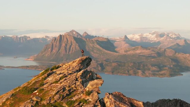 Norway climber on pointed arctic mountain with panorama glacier view; drone