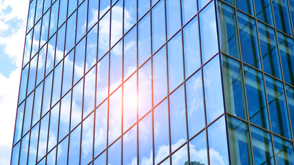 Fototapeta na wymiar Structural glass wall reflecting blue sky. Abstract modern architecture fragment. Glass building with transparent facade of the building and blue sky. Contemporary architectural background.