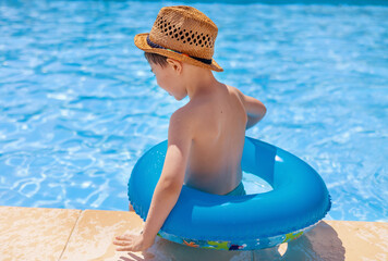 cute boy with beach sunny hat swimming in pool with inflatable ring tube.smiling adorable boy clean brite blu water summer vacation