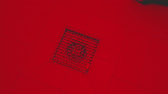 Cinematic red filter over drain for water on the floor of a professional kitchen, restaurant, school, factory, or canteen - slow rotation above 4k UHD