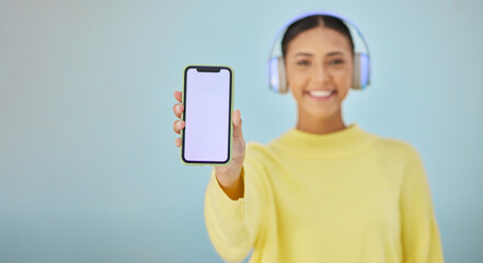 Happy woman with phone screen, headphones and mockup in studio for social media post, mobile app...