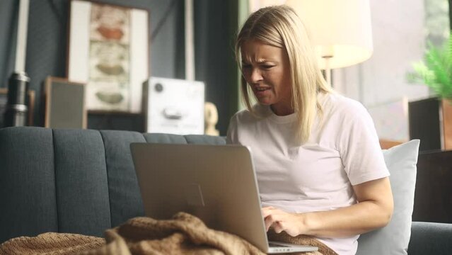 Nervous blond woman closed laptop computer with unsuccessful business project at home Angry mature businesswoman expressing negative emotion while has professional problem mistake error indoors
