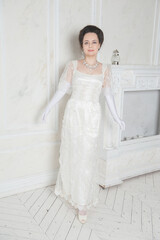 Beautiful young woman wearing medieval vintage Edwardian Style dress stand in the room