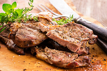 Traditional barbecued Greek lamb steak and shoulder with with herb and spice served as close-up on a wooden design board
