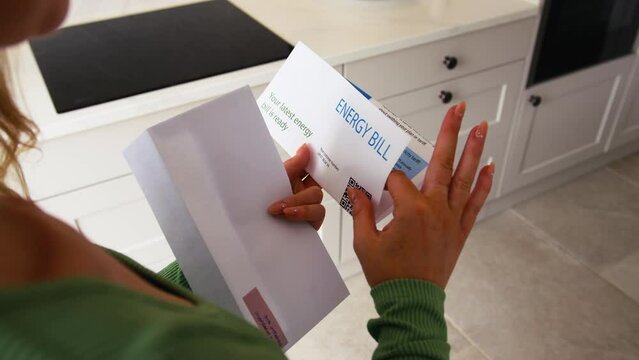 Close up of woman at home opening American dollar energy bill during cost of living crisis - shot in slow motion