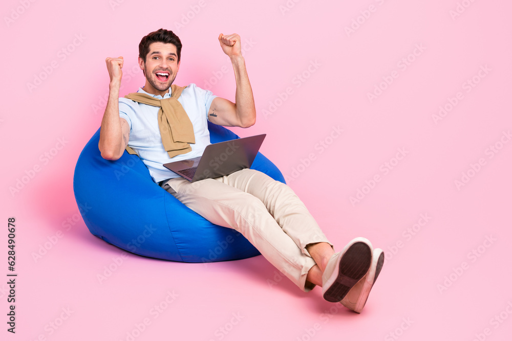 Aufkleber Full length portrait of delighted funny man sit comfort bag use netbook raise fists empty space isolated on pink color background