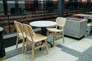 Empty tables with flowers in outdoor cafe or restaurant. Tables and chairs at sidewalk cafe. Touristic setting, sidewalk cafe furniture. High quality photo